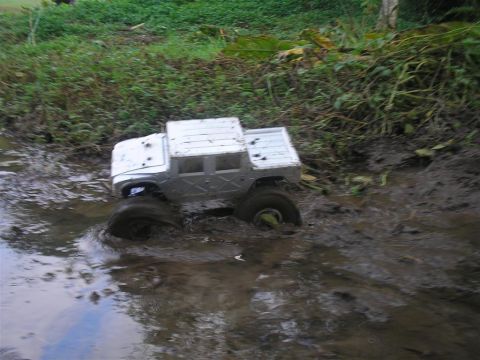 1994 Ford Escort - RC monster truck navigating a muddy trail.