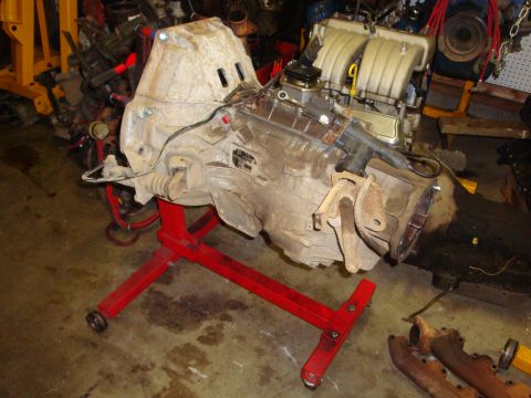 1989 Ford Bronco - Engine and transmission assembly mounted on a red engine stand in a workshop environment.