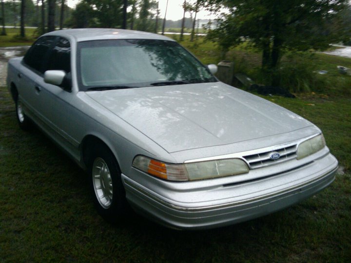 Silver sedan parked on grass, front 3/4 view. Headlights and grille visible