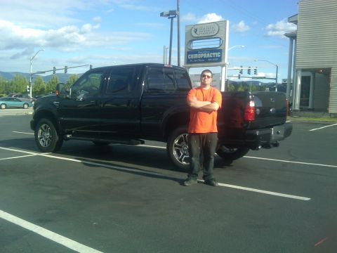 1988 Ford Bronco - A man stands beside a black Ford F-Series pickup truck in a parking lot.