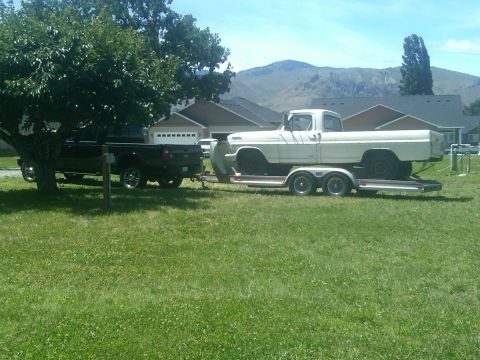 1988 Ford Bronco - A white 1970 Ford F-Series pickup truck is loaded onto a trailer towed by a black pickup truck.