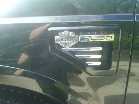 1988 Ford Bronco - A close-up of the "Super Duty F-250" emblem on the fender of a truck, a Harley-Davidson logo.