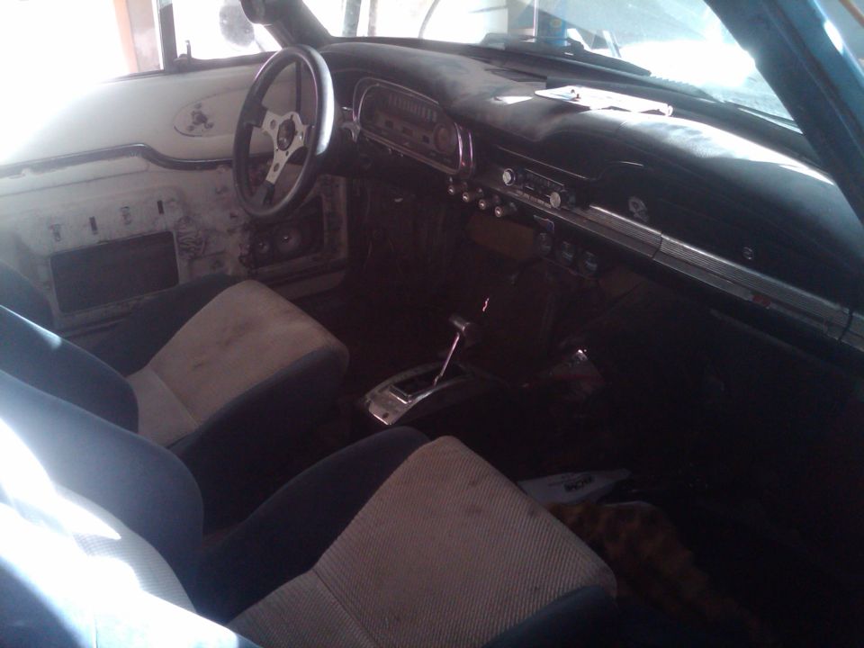 Stripped project car interior with round gauge cluster, sport steering wheel and cloth seats