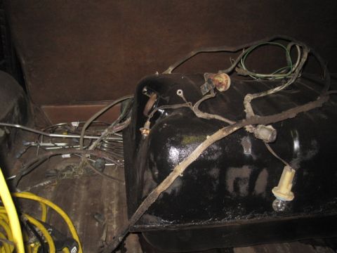 1979 Ford Bronco - Close-up view of a vehicle's fuel tank and associated wiring, likely from underneath or inside the cargo area.