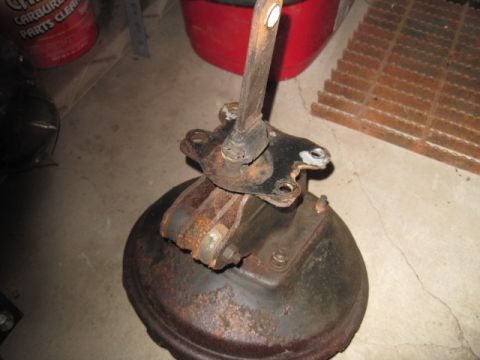 1979 Ford Bronco - A rusty brake booster and master cylinder assembly, likely for an older vehicle, sits on a concrete floor.