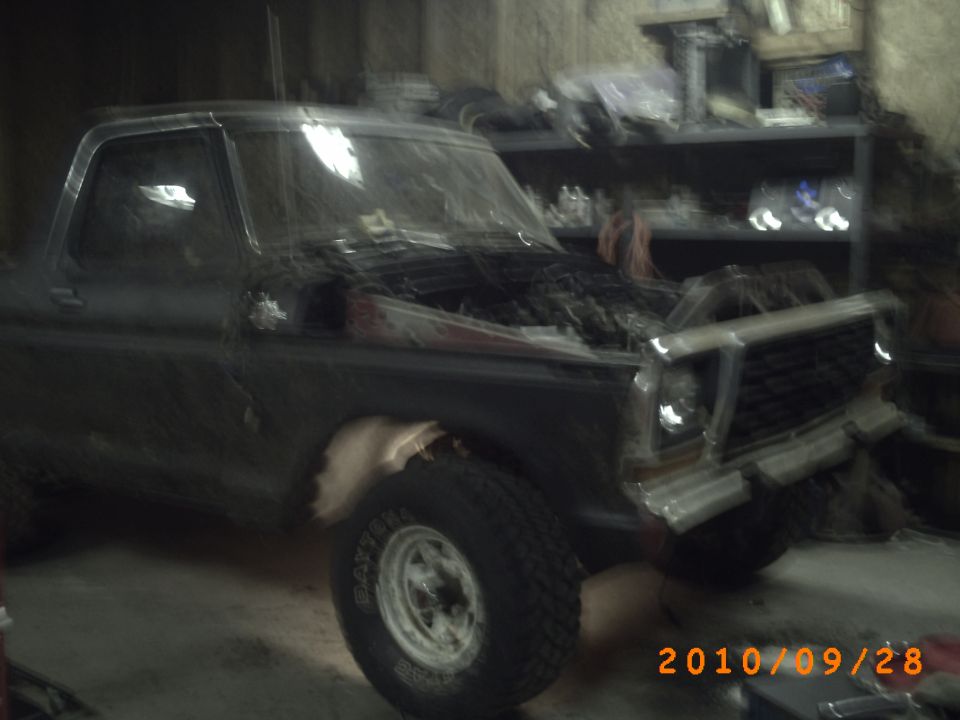 Dark 1978 Ford Bronco with hood open, showing engine, in a garage