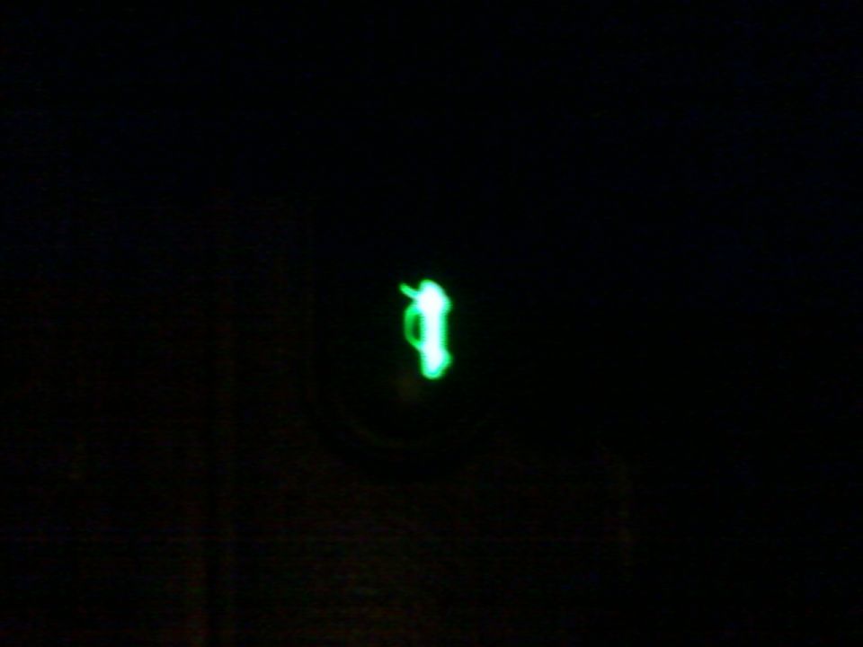 glowing green symbol on black background, supermotors.net watermark