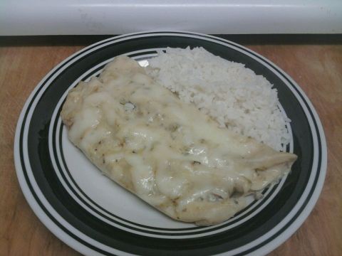 1989 Ford Bronco - A plate of chicken covered in cheese and a side of white rice sits on a wooden surface.