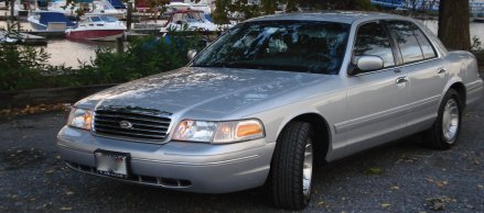 2000 Ford Crown Victoria - Silver 2000 Ford Crown Victoria parked near a marina with boats in the background.