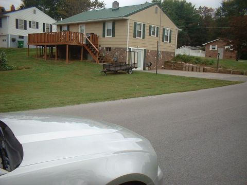1971 Ford Ranchero - A silver car's hood is visible in the foreground, with a residential house and yard in the background.