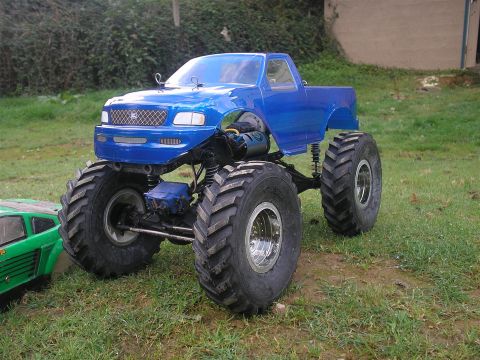 1994 Ford Escort - Blue RC monster truck with large tires, parked next to a green RC car.