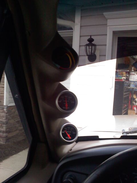 1977 Ford F-100 - A-pillar gauge pod with two gauges showing readings, mounted inside a vehicle.