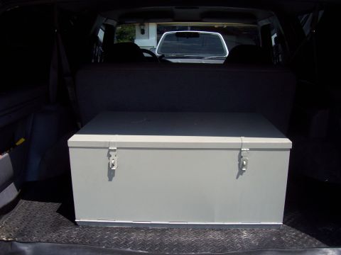 1994 Ford Bronco - Storage chest placed in the rear of an SUV, obscuring the view of another vehicle outside.
