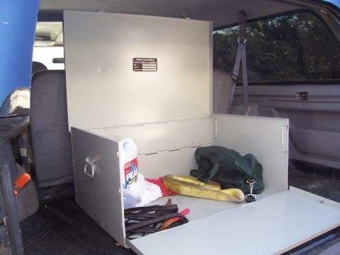 1994 Ford Bronco - The interior of a vehicle's cargo area shows an open metal storage box with various items inside.