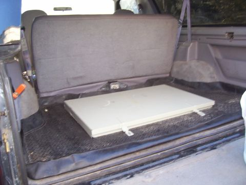 1994 Ford Bronco - The rear storage area of a 1994 Ford Bronco, showing the folded rear seat and a removable cargo cover.