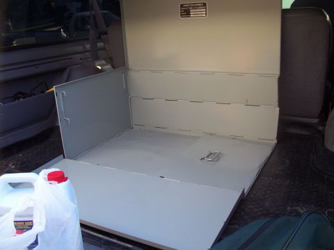 1994 Ford Bronco - Unfolded collapsible storage chest inside a vehicle's rear cargo area, with a jug of liquid visible.