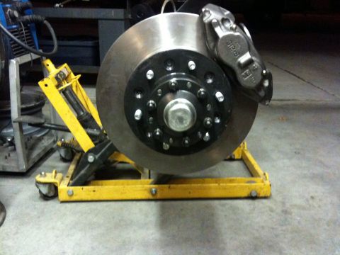 Suzuki Samurai - Brake rotor and caliper assembly on a yellow stand, with visible text on the caliper.