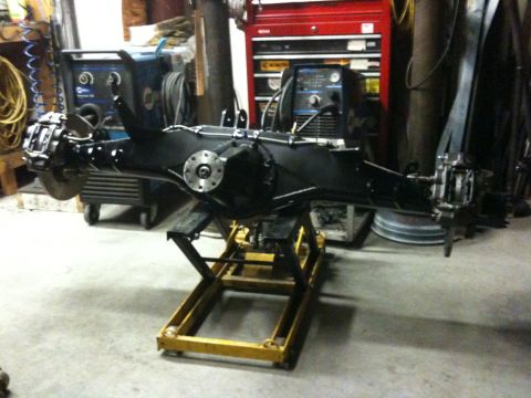 Suzuki Samurai - A black rear axle assembly is shown on a yellow lift in a workshop setting.