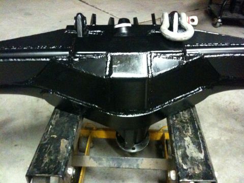 Suzuki Samurai - A black rear axle assembly, possibly for an off-road vehicle, is shown mounted on a stand. The assembly features prominent tow hooks.
