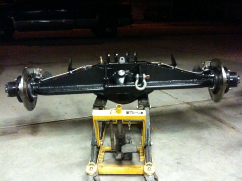 Suzuki Samurai - A black rear axle assembly with disc brakes is mounted on a yellow jack.