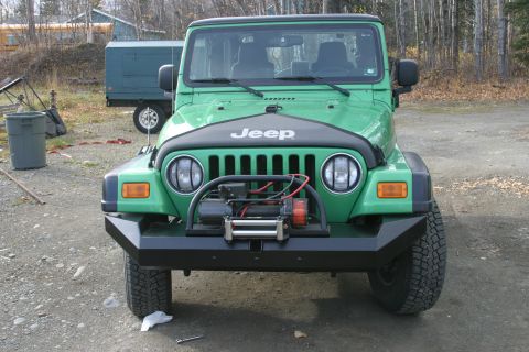 1987 Suzuki Samurai - Front view of a green Jeep Wrangler equipped with a winch and a heavy-duty aftermarket bumper.
