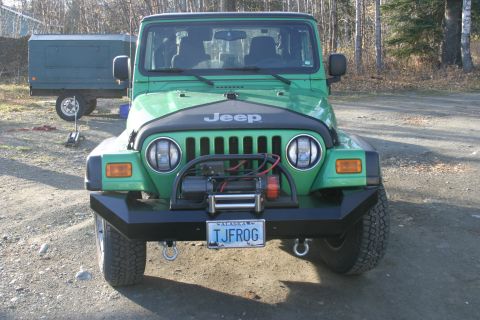 1987 Suzuki Samurai - Front view of a green Jeep Wrangler equipped with a winch and custom bumper.