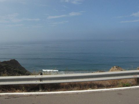 1986 Ford Bronco - A scenic view of the ocean with a guardrail in the foreground and a watermark indicating the source as SUPERMOTORS.
