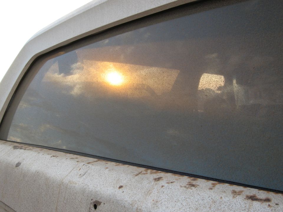 Sunlight reflects off the dusty interior window of a vehicle