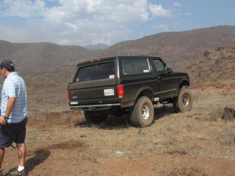 1986 Ford Bronco - This Ford Bronco is parked on a dusty, arid hillside with a man standing nearby.
