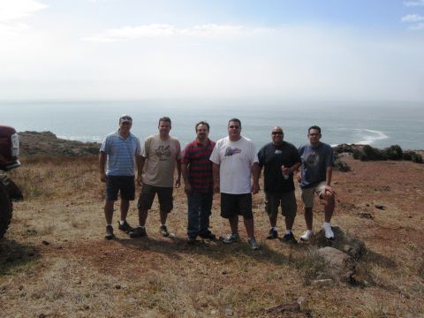 1986 Ford Bronco - A group of men pose for a photo on a coastal hill next to a red vehicle.