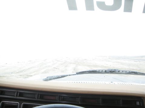 1986 Ford Bronco - Driving through a snowstorm, the road ahead is obscured by whiteout conditions.