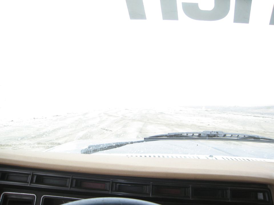 view from inside vehicle looking out at snowy road, dashboard visible