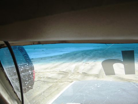 1986 Ford Bronco - View from inside a vehicle as it drives through a sandy area, with tire tracks visible on the ground.