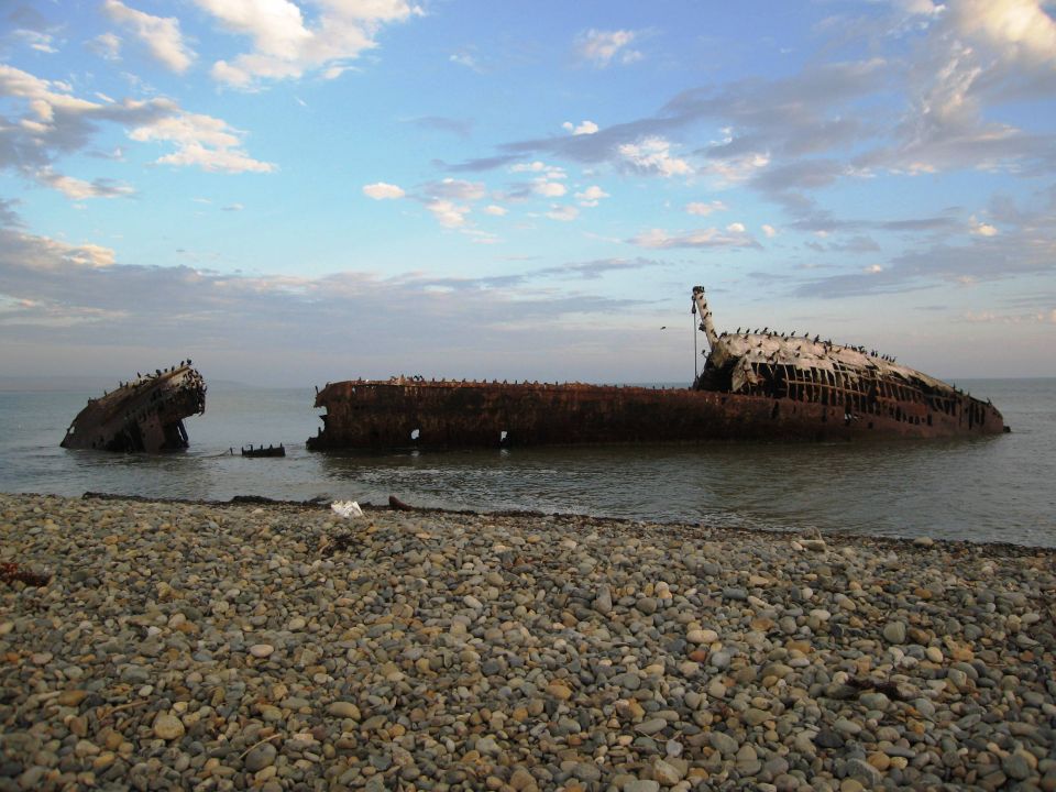 Shipwreck on a pebble beach under a cloudy sky
