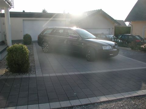 2003 Audi A6 - A black Audi A6 wagon is parked in a driveway in front of a garage. Another vehicle is visible behind it.