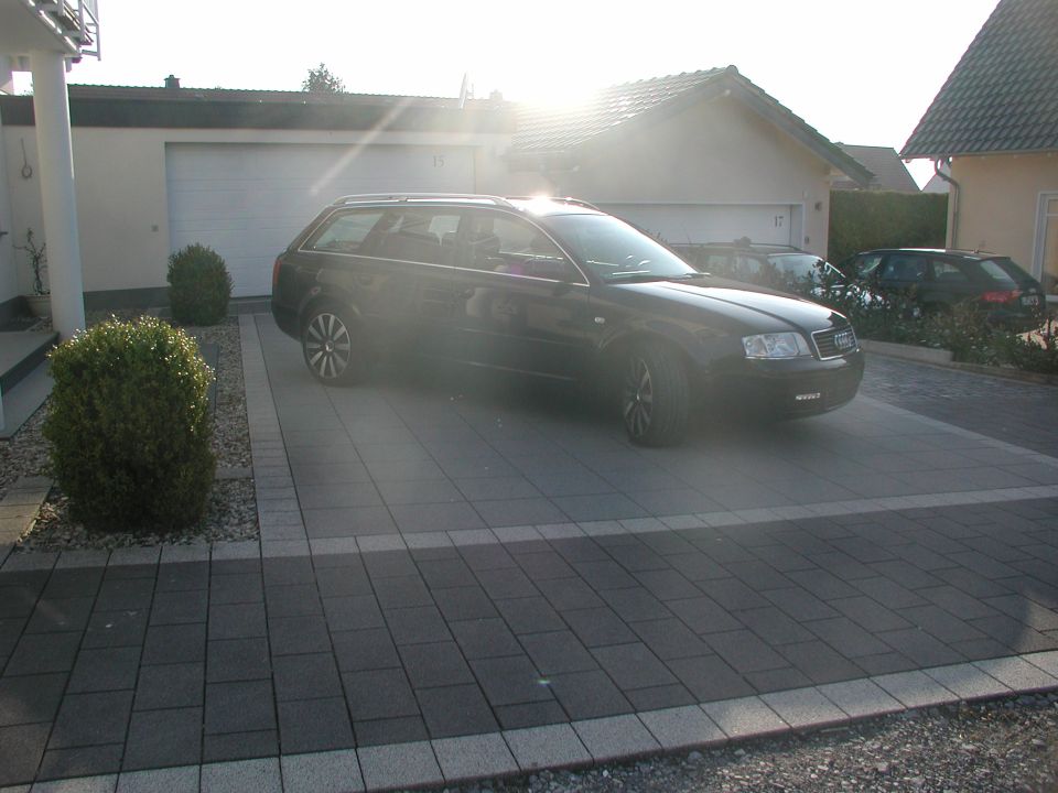 Black Audi A6 wagon parked in driveway, another car in background