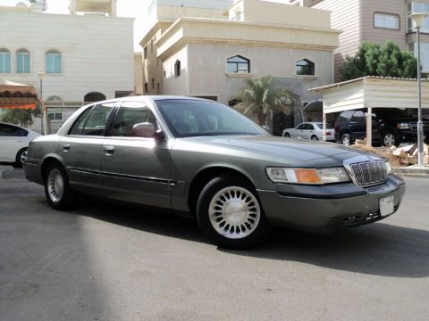 2001 Mercury Grand Marquis - Gray 2001 Mercury Grand Marquis sedan parked on a street with buildings in the background.