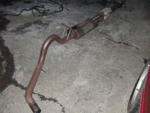 1986 Ford Bronco - Exhaust system part shown on a concrete floor, likely in a garage or workshop.