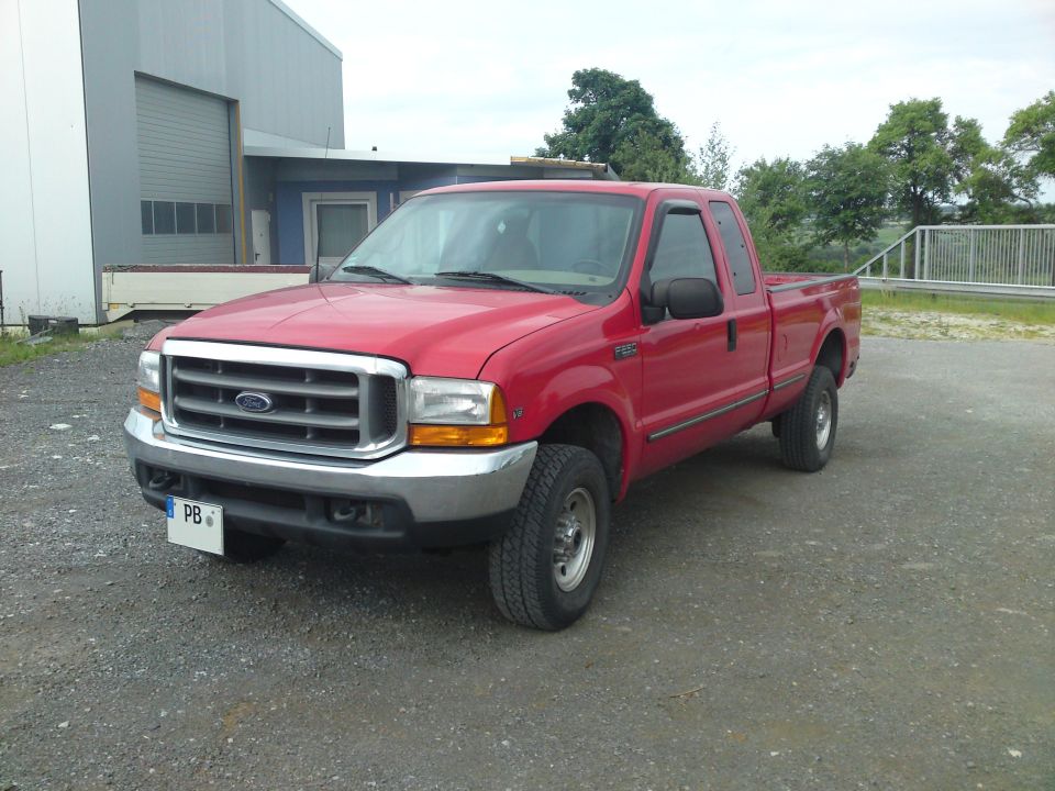 Red 1999 Ford F-250 Super Duty pickup truck parked outside a building