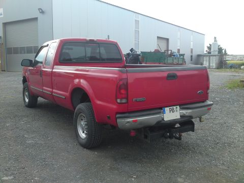 1999 Lincoln Town Car - The rear of a red Ford F-250 pickup truck is shown parked on a gravel lot.