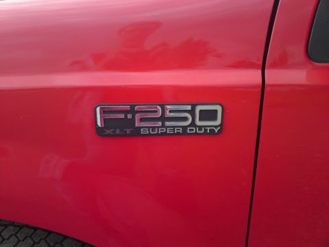 1999 Lincoln Town Car - Close-up of a red Ford F-250 XLT Super Duty fender badge.