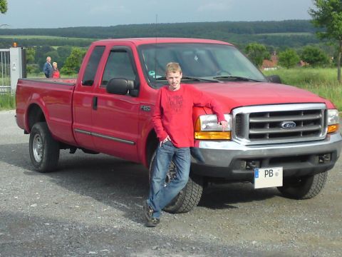 1999 Lincoln Town Car - A young man poses with a red Ford F-250 pickup truck in an outdoor setting.