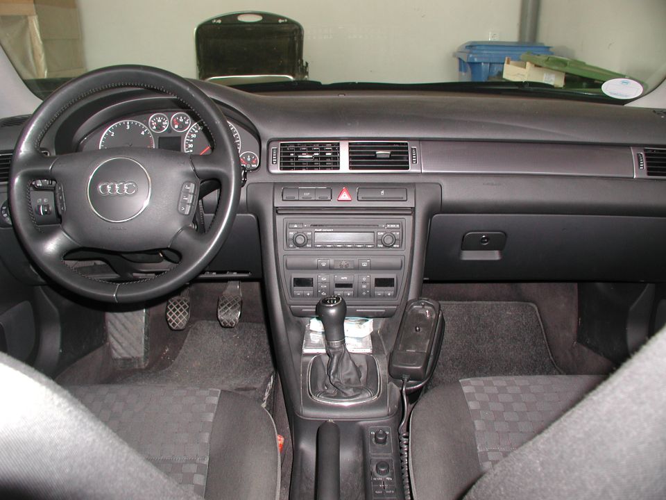 Gray interior dashboard of an Audi with manual shifter and four-ring logo