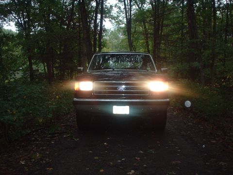 1989 Ford Bronco - Front view of a 1989 Ford Bronco parked on a dirt road at dusk.