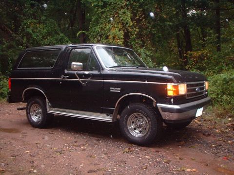 1989 Ford Bronco - This 1989 Ford Bronco is parked on a dirt road surrounded by trees.