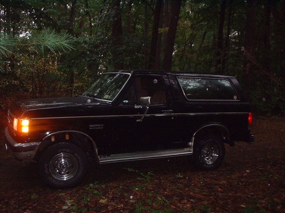 1989 Ford Bronco parked on a dirt path in the woods