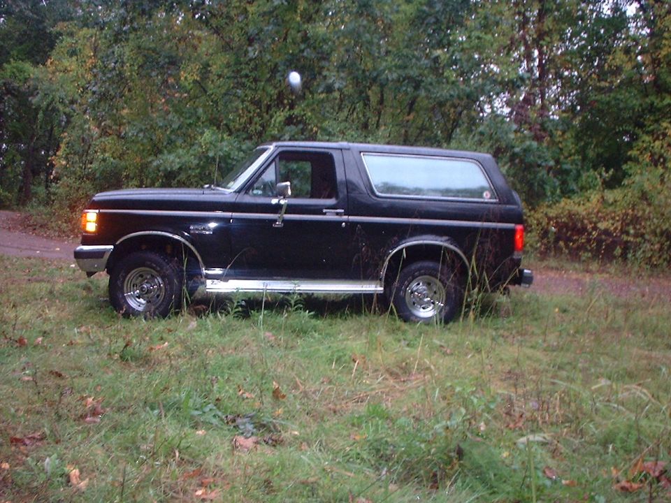 1989 Ford Bronco parked on grass with trees in background