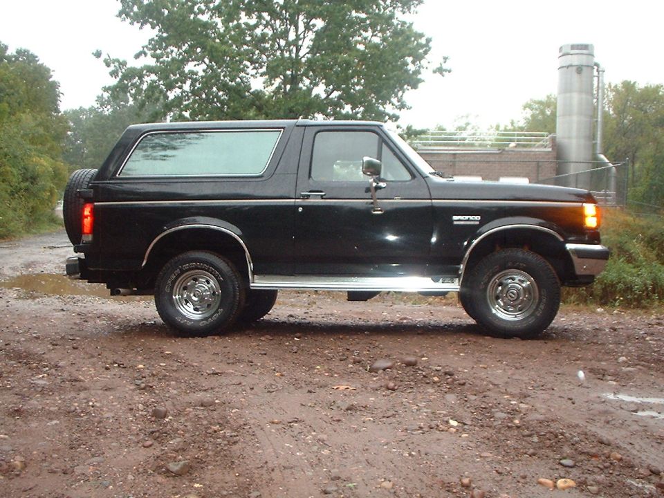 Black Ford Bronco SUV, side view, with chrome trim and a spare tire mounted on the rear door