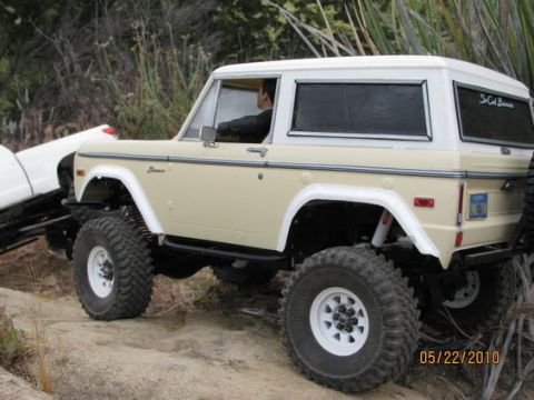 1988 Ford Bronco - A remote-controlled Ford Bronco navigates a rocky trail, with another vehicle partially visible behind it.