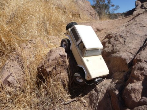 1988 Ford Bronco - A remote-controlled vehicle navigates a rocky, off-road terrain under a clear blue sky.